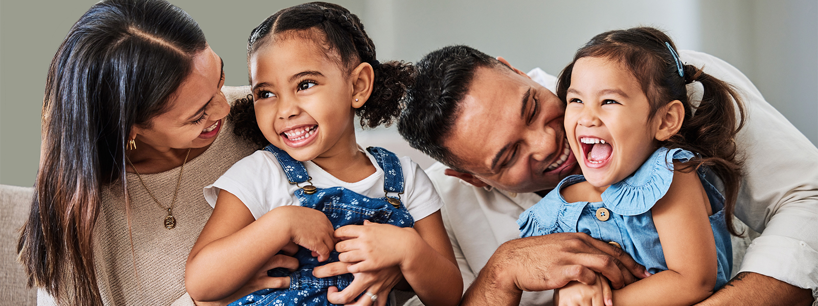 parents and small children sitting on couch together and laughing while enjoying quality time together